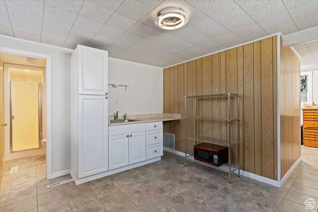 Bar area with wood walls, ornamental molding, and light tile patterned floors