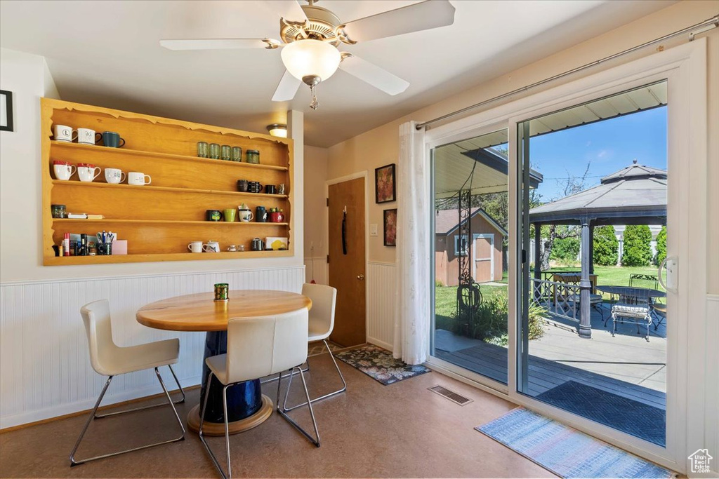 Dining space with a wainscoted wall, a ceiling fan, and built in features