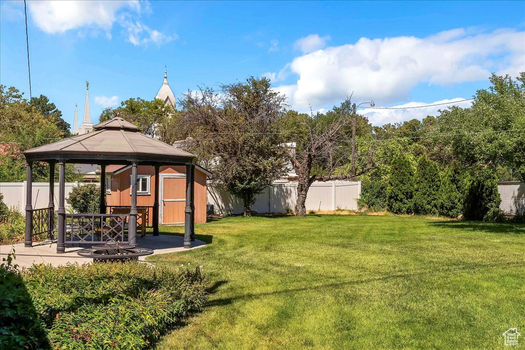 Fenced backyard featuring a gazebo, a patio area, and a fire pit