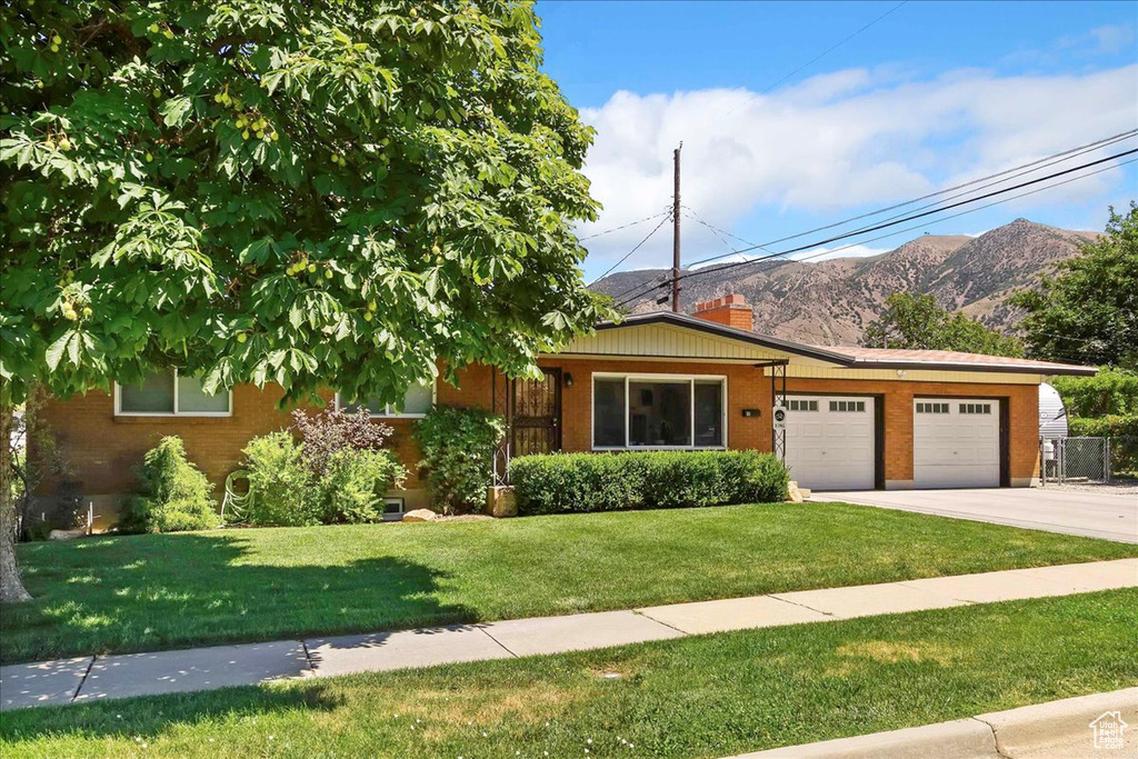 View of front of home featuring an attached garage, a front lawn, brick siding, and concrete driveway