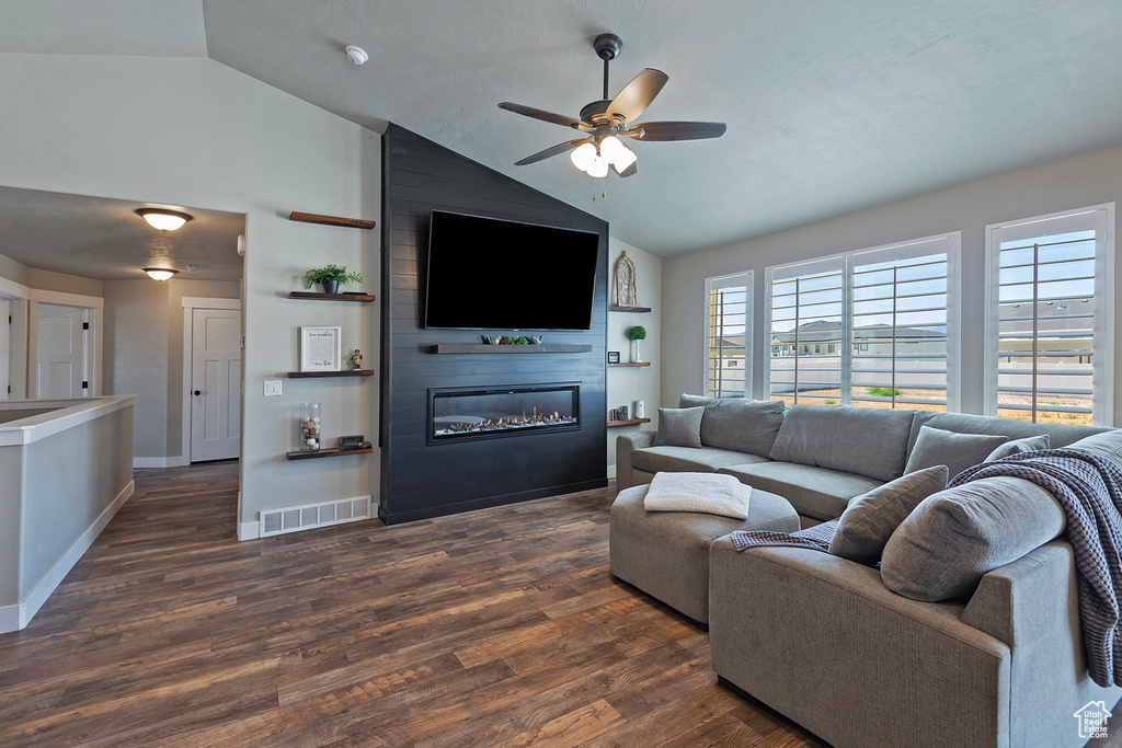 Living area featuring a ceiling fan, a fireplace, dark wood-style floors, and high vaulted ceiling