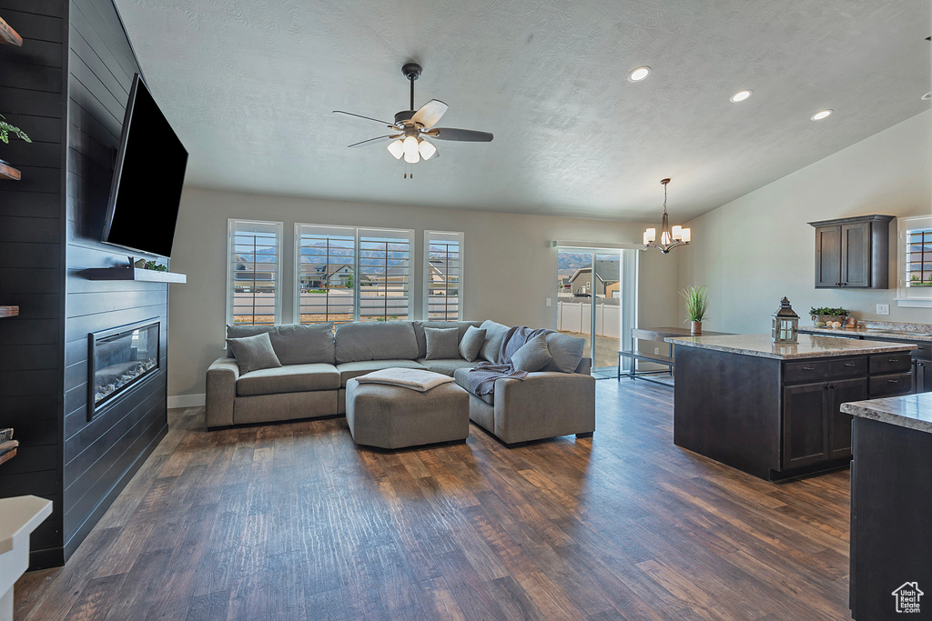 Living room with ceiling fan, dark wood-style floors, healthy amount of natural light, a fireplace, and lofted ceiling
