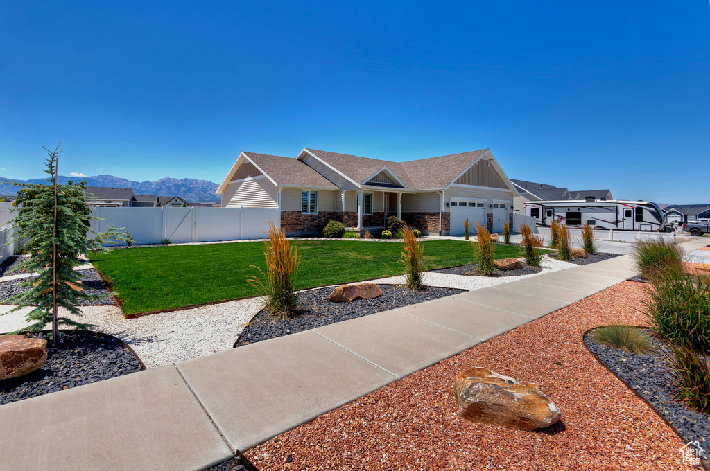 View of front of home featuring an attached garage, a mountain view, roof with shingles, stone siding, and a residential view