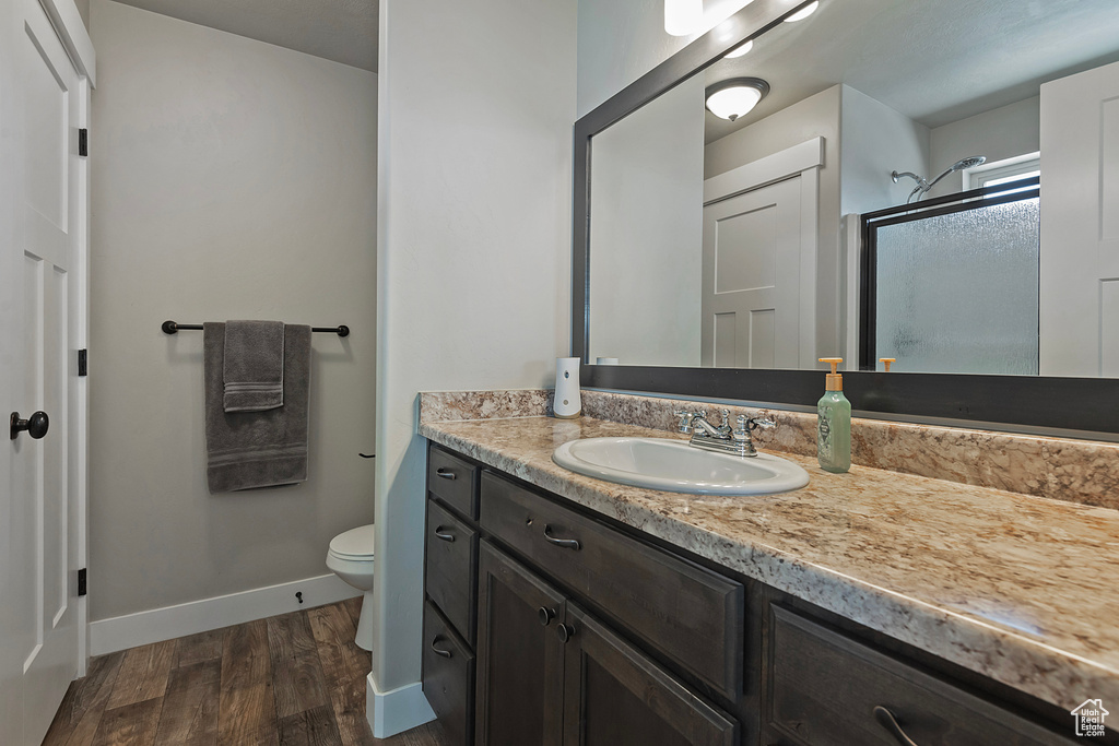 Bathroom with vanity, wood finished floors, and an enclosed shower