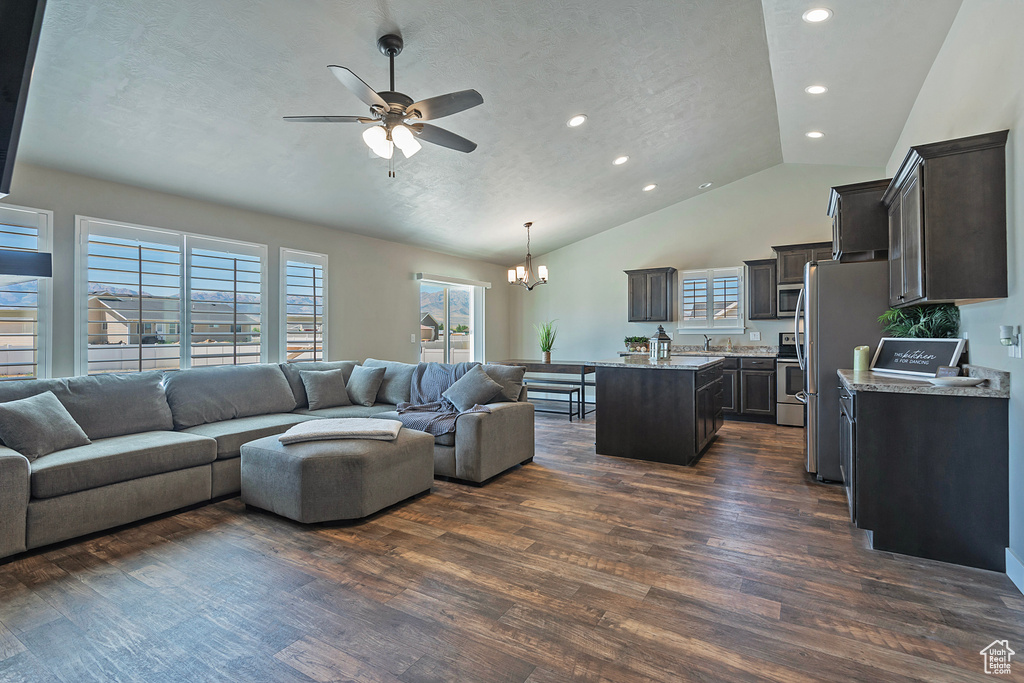 Living room featuring a chandelier, ceiling fan, dark wood-style flooring, lofted ceiling, and recessed lighting