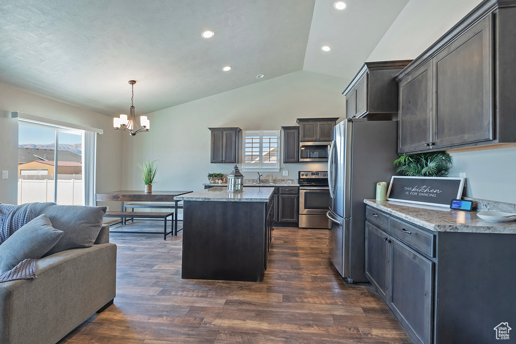 Kitchen with a center island, a chandelier, open floor plan, lofted ceiling, and appliances with stainless steel finishes