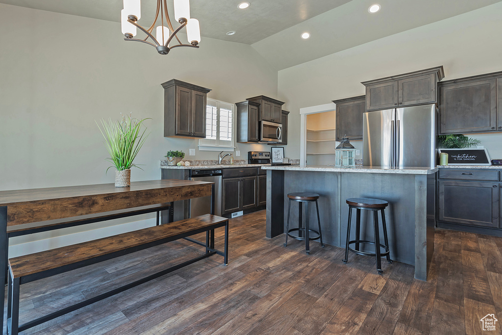 Kitchen featuring a kitchen island, dark brown cabinetry, a breakfast bar, appliances with stainless steel finishes, and recessed lighting