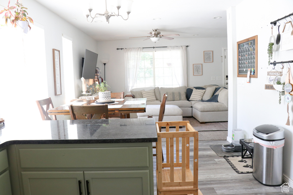 Living area featuring light wood-style flooring, a ceiling fan, a chandelier, and recessed lighting