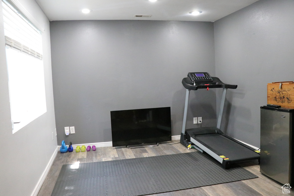 Exercise area with wood finished floors and recessed lighting