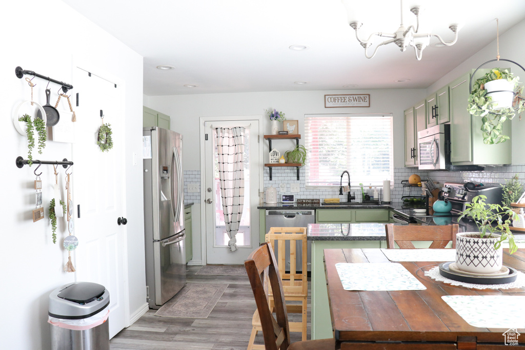 Kitchen featuring green cabinetry, a chandelier, dark countertops, stainless steel appliances, and light wood-type flooring