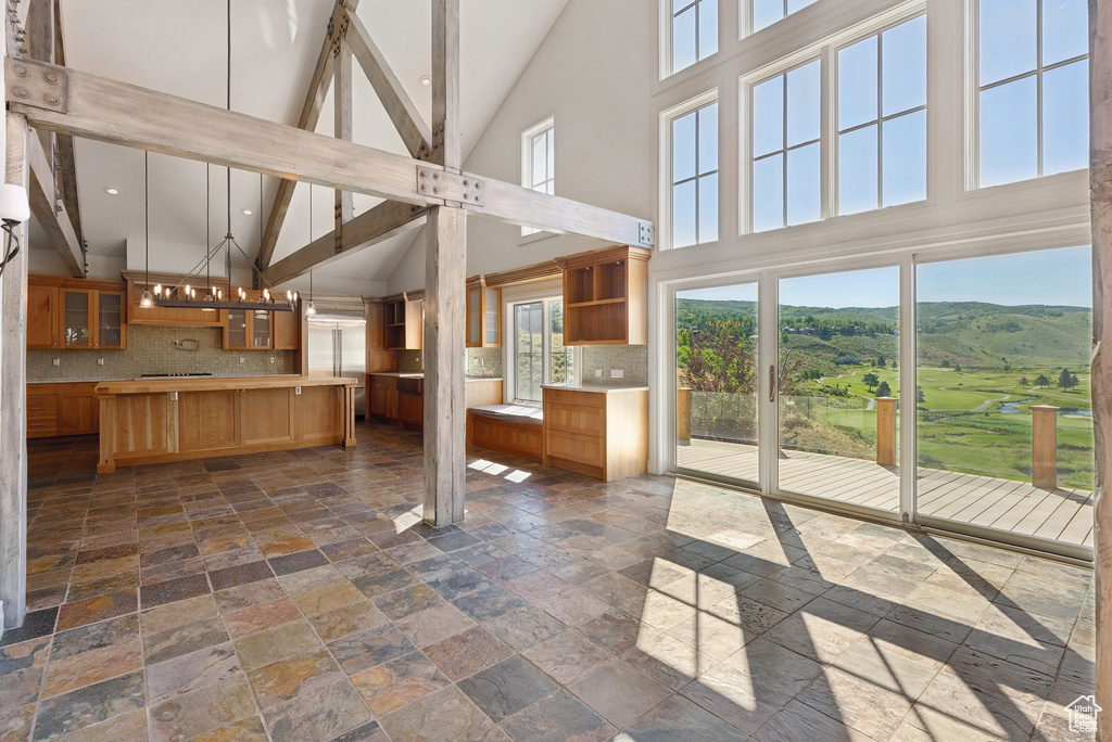 Kitchen with high vaulted ceiling, stone tile flooring, light countertops, decorative backsplash, and recessed lighting