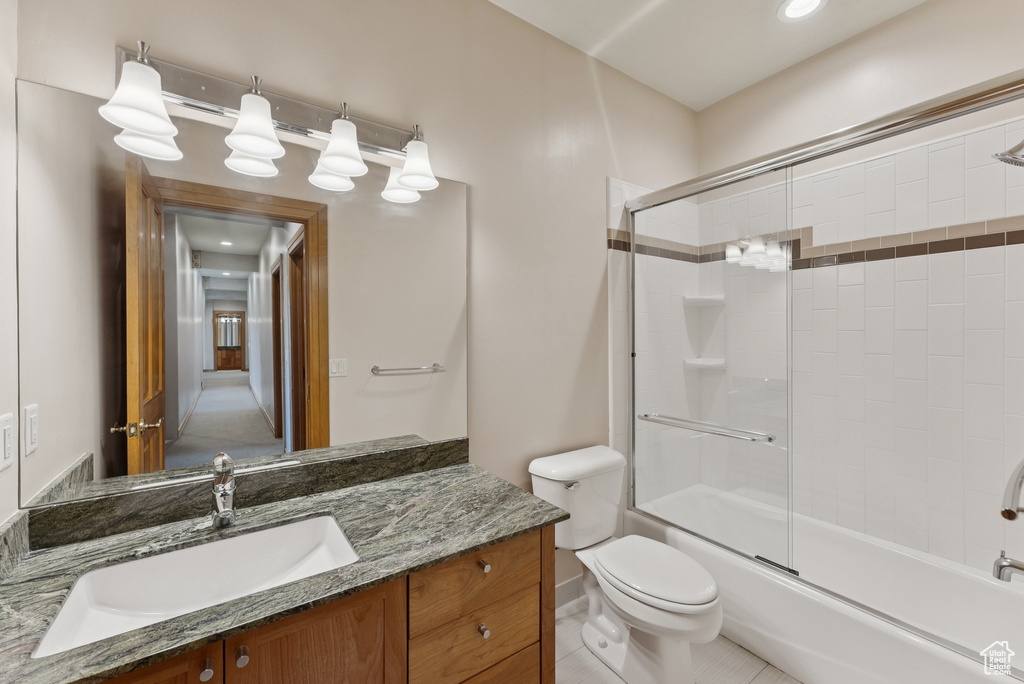 Full bath featuring vanity, bath / shower combo with glass door, and tile patterned floors
