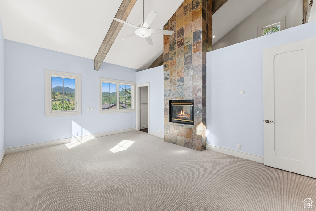 Unfurnished living room featuring high vaulted ceiling, carpet flooring, ceiling fan, beam ceiling, and a fireplace