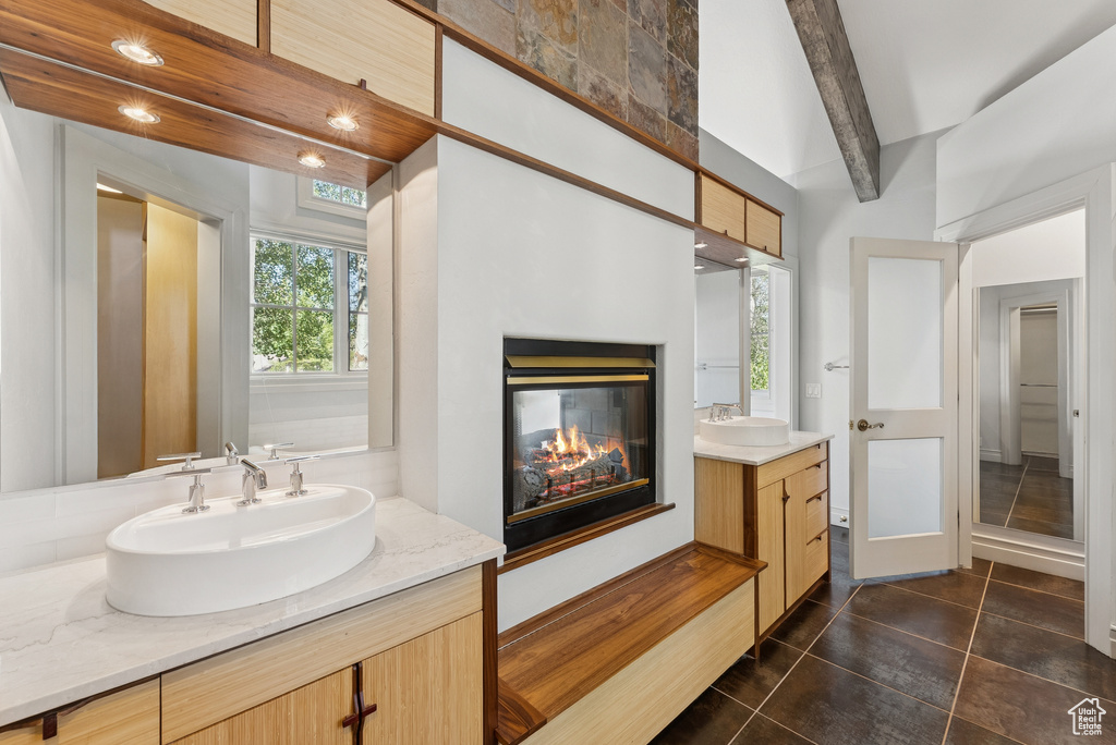 Bathroom featuring two vanities, a multi sided fireplace, and tile patterned floors