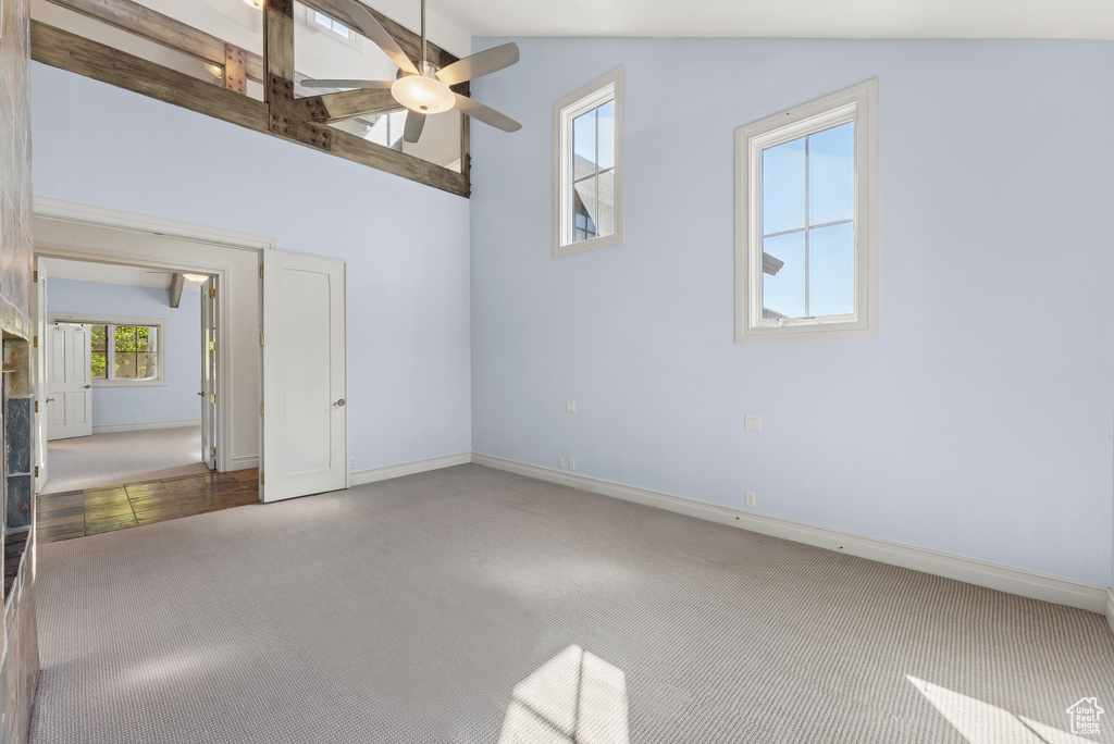 Carpeted empty room with ceiling fan and vaulted ceiling