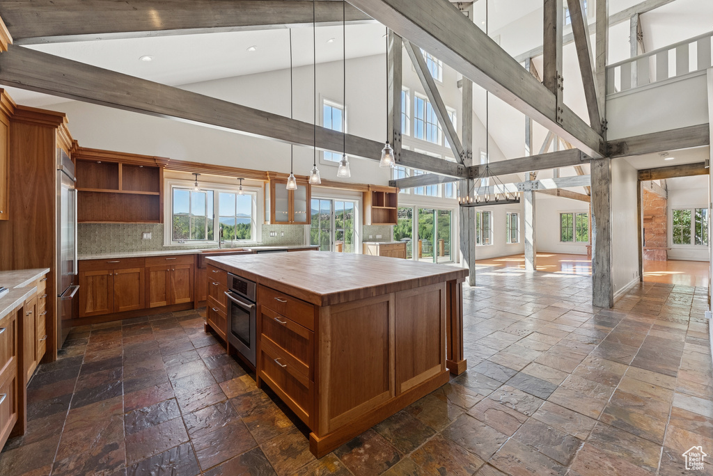 Kitchen with stone tile flooring, open shelves, butcher block counters, healthy amount of natural light, and tasteful backsplash