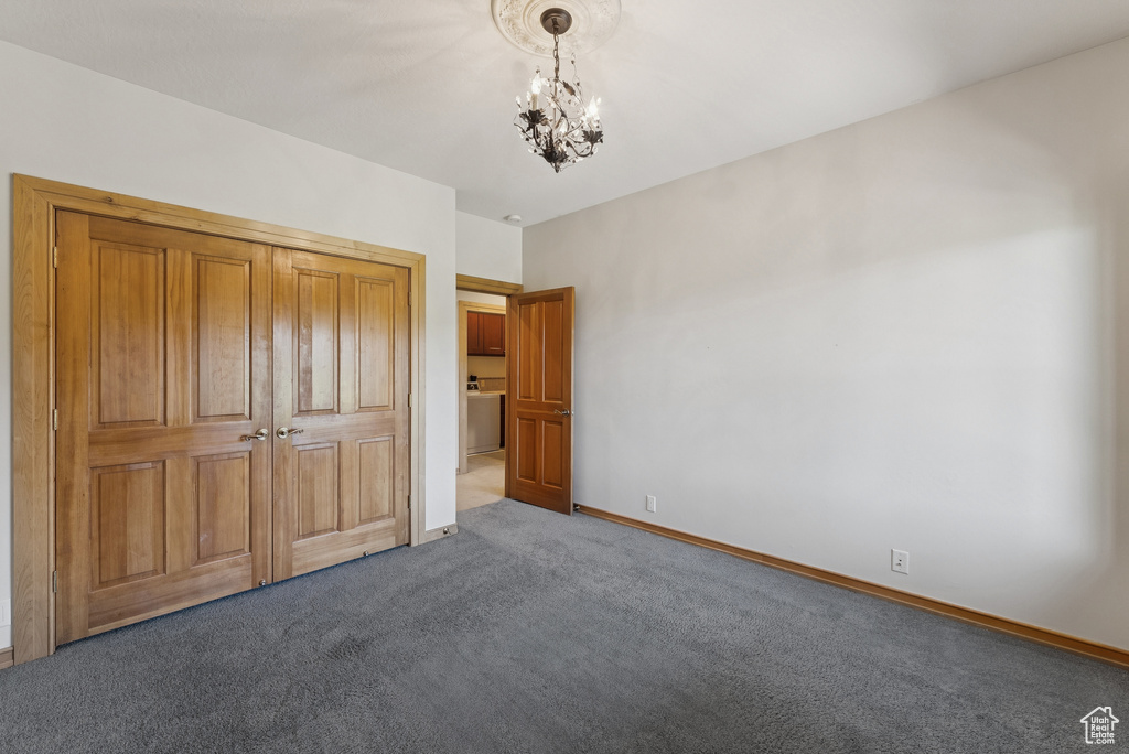 Unfurnished bedroom featuring carpet flooring and a chandelier