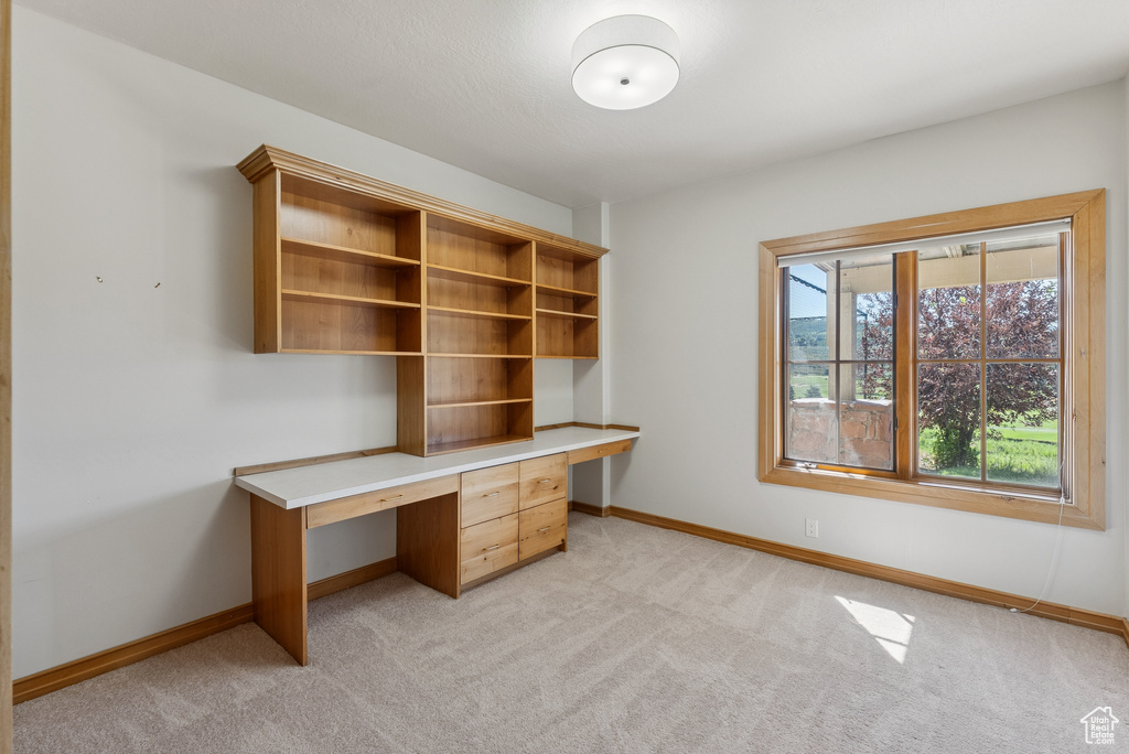 Unfurnished office with built in desk and light colored carpet