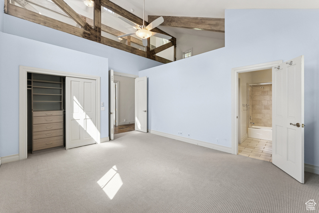Unfurnished bedroom with carpet floors, high vaulted ceiling, beam ceiling, a closet, and connected bathroom
