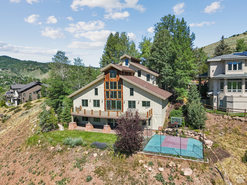 Back of property featuring board and batten siding, a patio, and basketball hoop