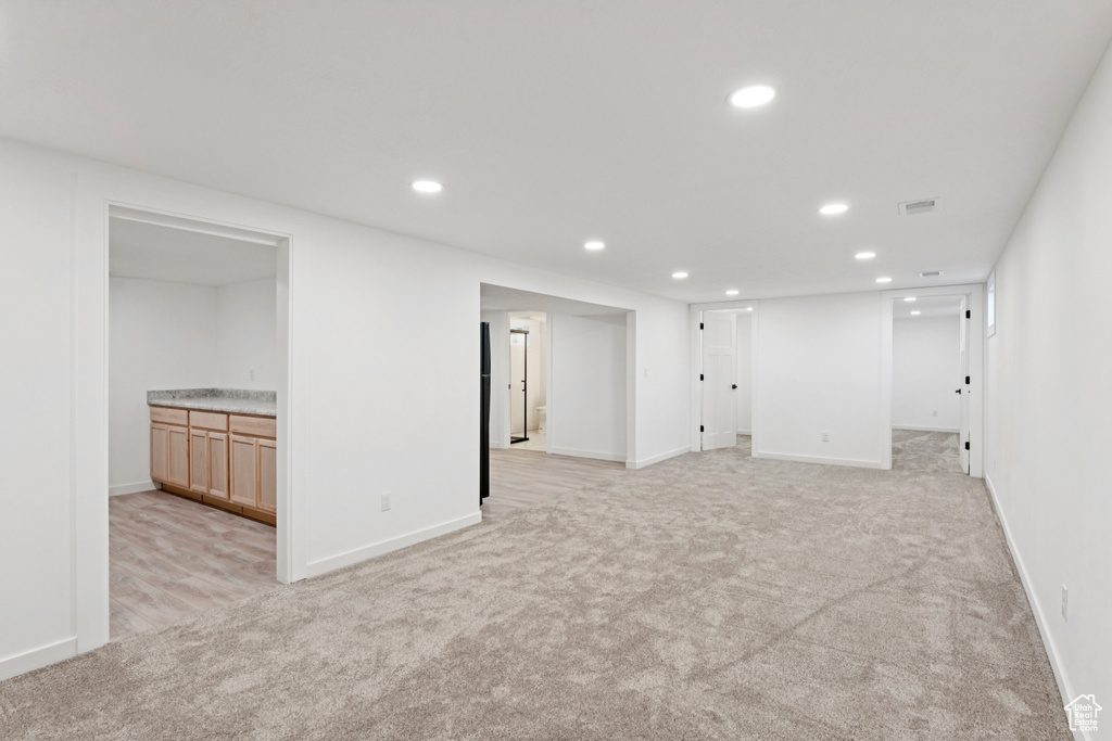 Finished below grade area featuring light carpet, recessed lighting, and bar