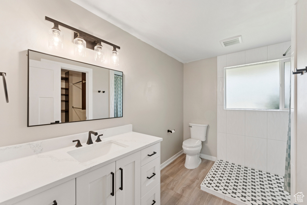 Bathroom with vanity, tiled shower, and wood finished floors