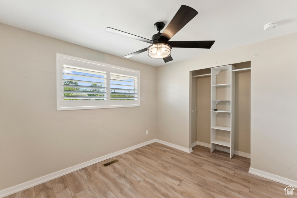 Unfurnished bedroom featuring light wood-style floors, a ceiling fan, and a closet