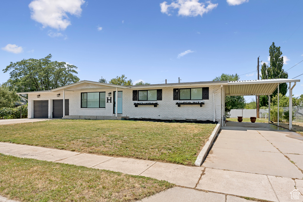 Ranch-style house featuring concrete driveway, brick siding, an attached carport, and an attached garage