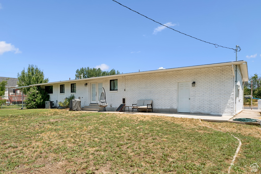 Back of house featuring a lawn, entry steps, brick siding, and a patio