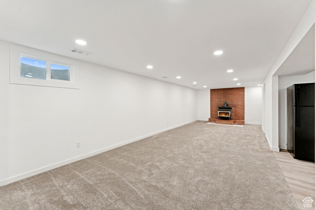 Basement with freestanding refrigerator, a fireplace, recessed lighting, and light colored carpet