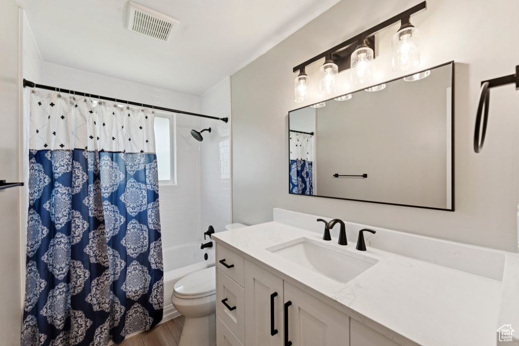 Full bath featuring vanity, wood finished floors, and shower / bath combination with curtain