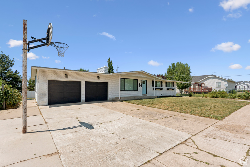 Single story home with brick siding, driveway, a chimney, a garage, and a front lawn