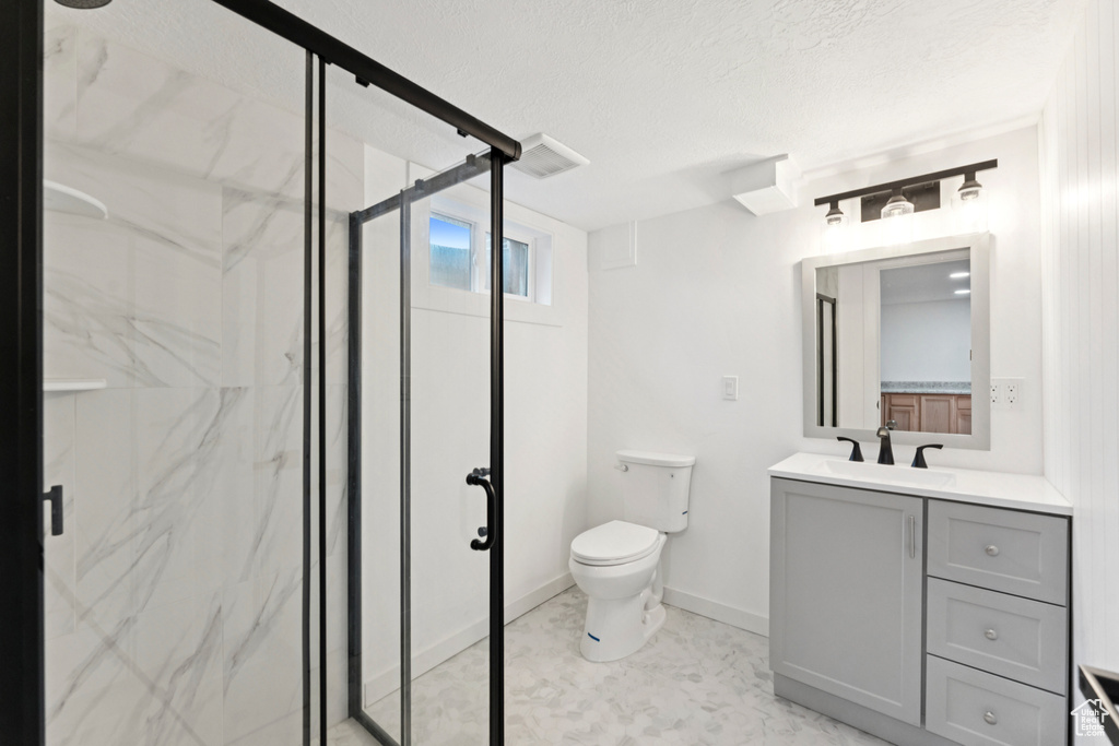 Full bath featuring a marble finish shower, vanity, and a textured ceiling