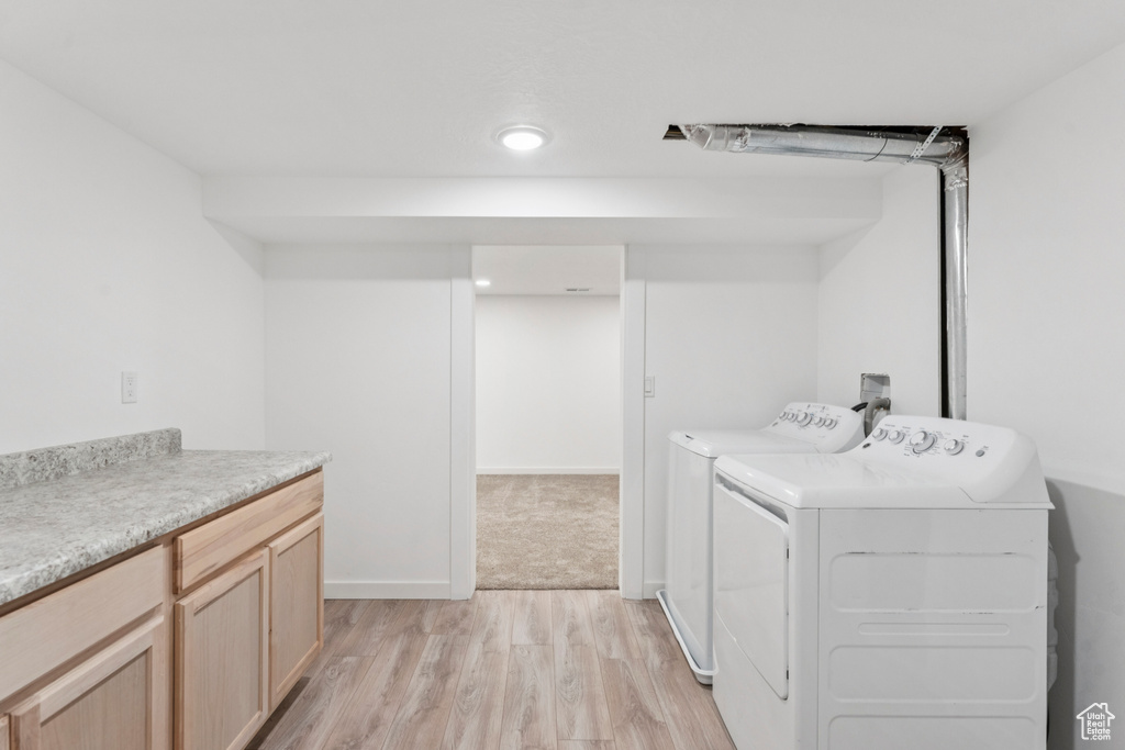 Washroom featuring washing machine and dryer, light wood-style flooring, cabinet space, and recessed lighting