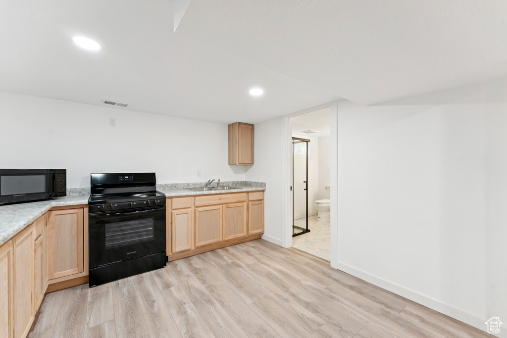 Kitchen featuring light brown cabinets, black appliances, light wood-type flooring, light countertops, and recessed lighting