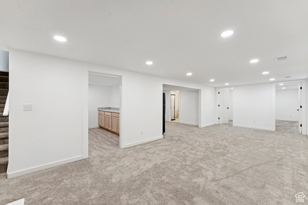 Finished below grade area featuring stairs, light colored carpet, and recessed lighting