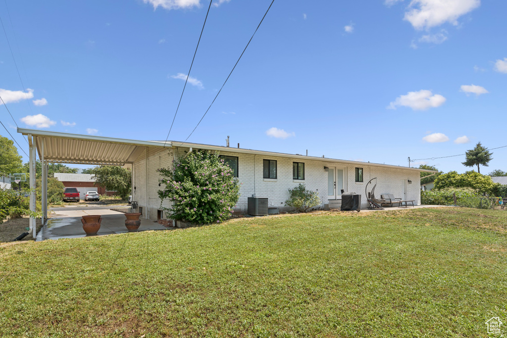 Rear view of property with an attached carport, a yard, and brick siding
