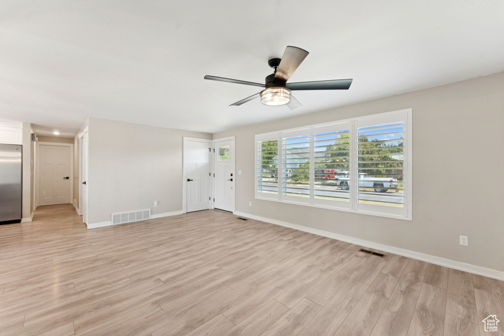 Unfurnished living room with light wood-style floors and a ceiling fan