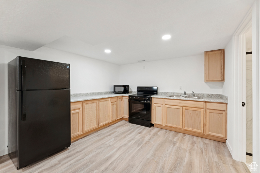 Kitchen featuring light brown cabinetry, black appliances, light wood-style flooring, light countertops, and recessed lighting