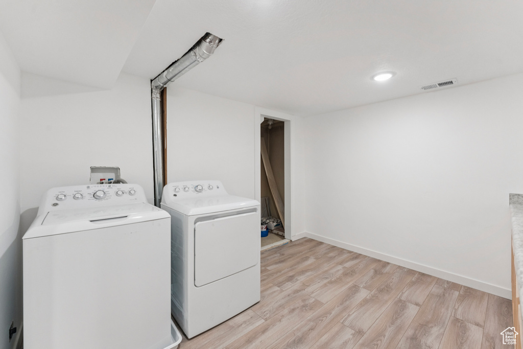 Laundry room with independent washer and dryer and light wood finished floors