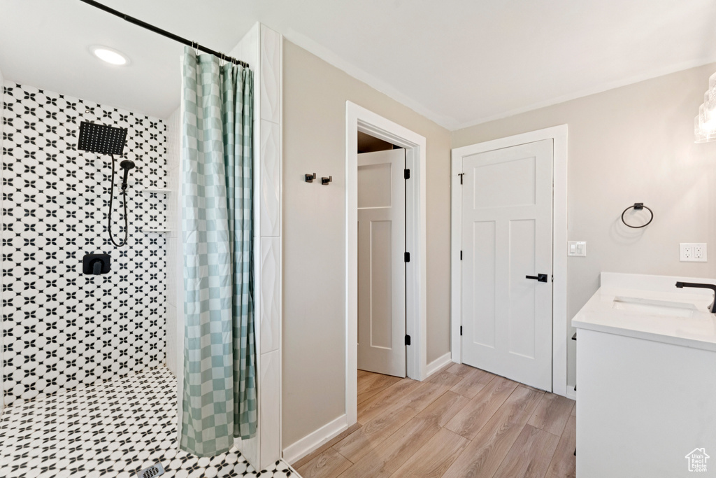 Full bath with a shower stall, wood finished floors, double vanity, and recessed lighting