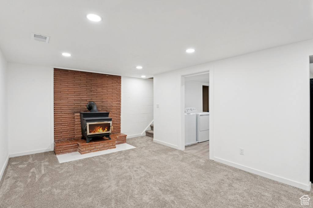 Unfurnished living room featuring washing machine and clothes dryer, carpet flooring, stairway, recessed lighting, and a wood stove