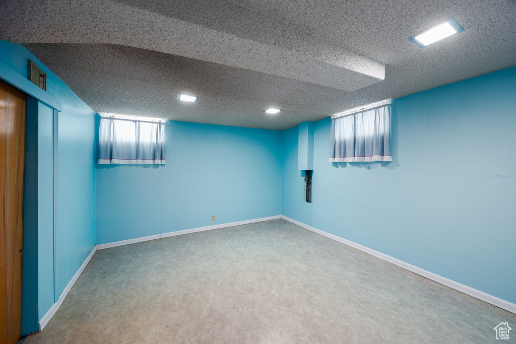 Below grade area with a textured ceiling and carpet flooring