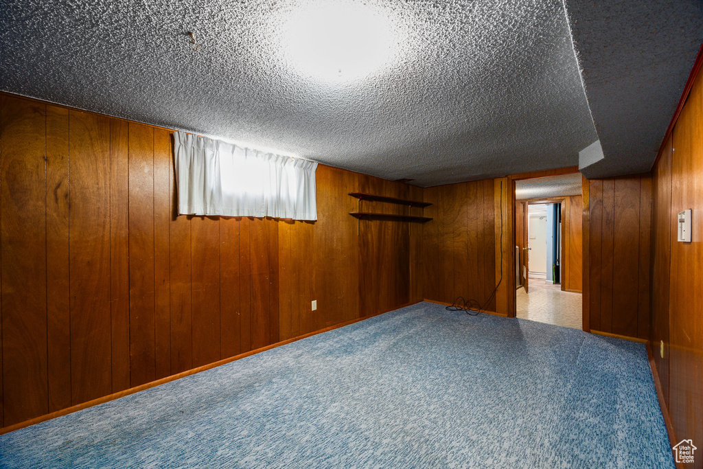 Empty room with a textured ceiling and wood walls