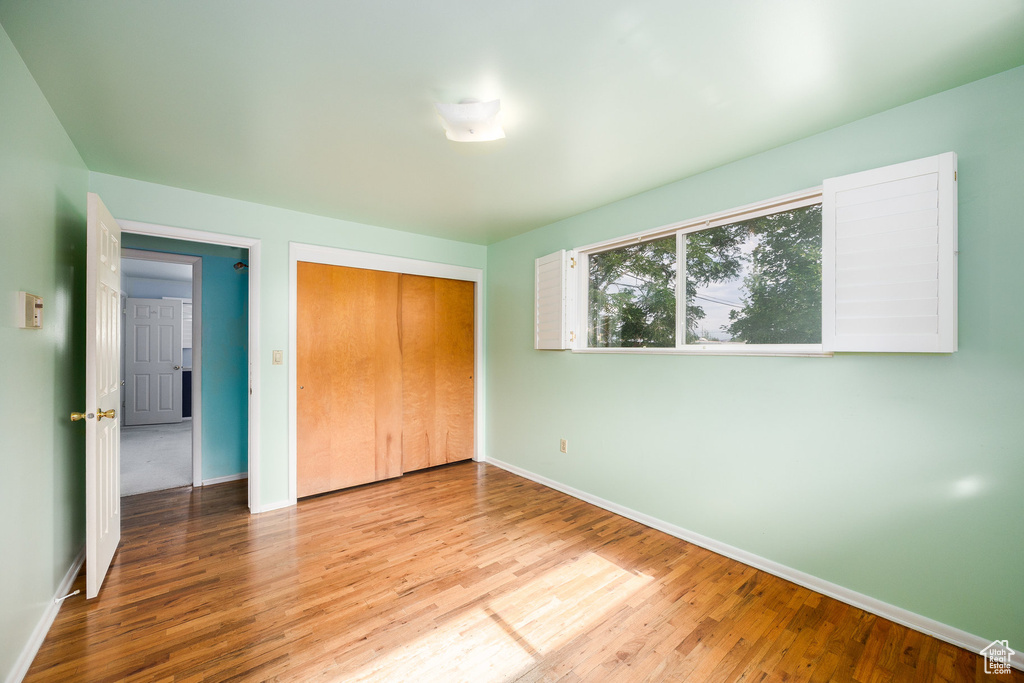 Unfurnished bedroom with wood finished floors and a closet
