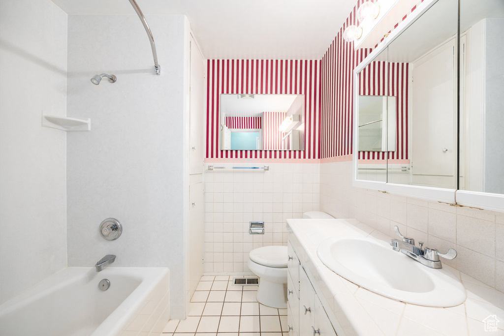 Full bath with tile patterned flooring, vanity, bathing tub / shower combination, and tile walls