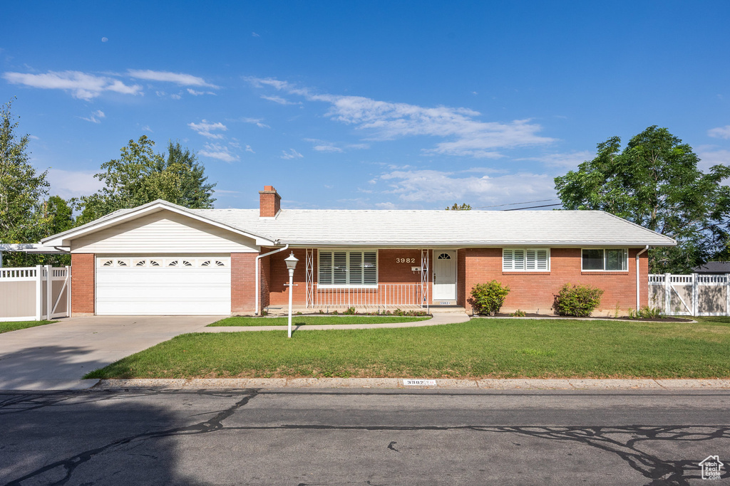 Ranch-style home with a garage, driveway, a chimney, and brick siding