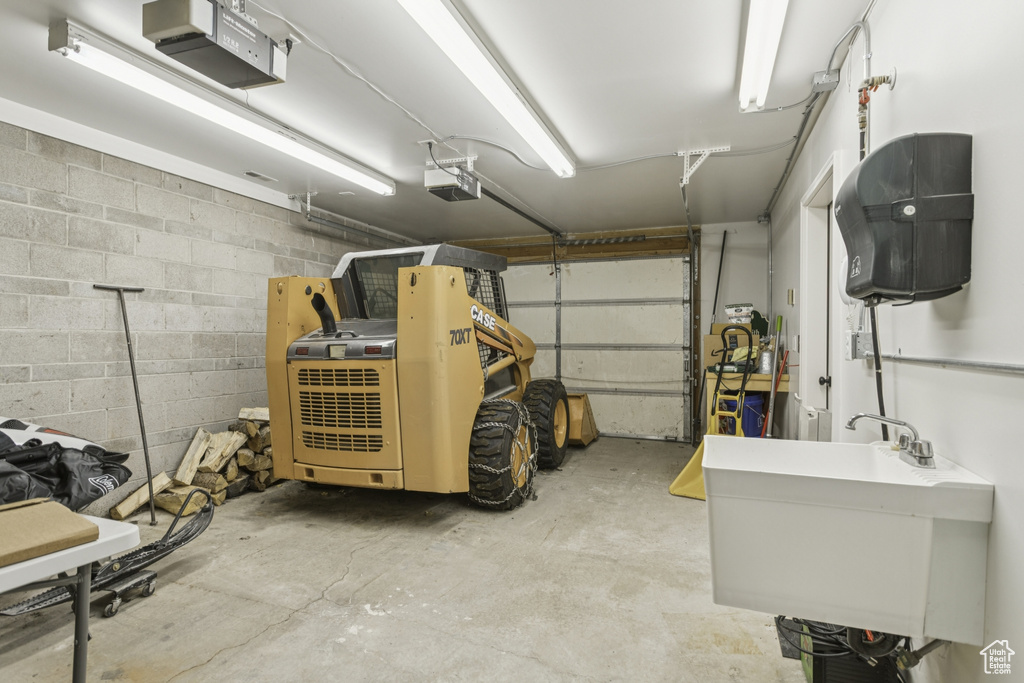 Garage featuring a garage door opener and concrete block wall