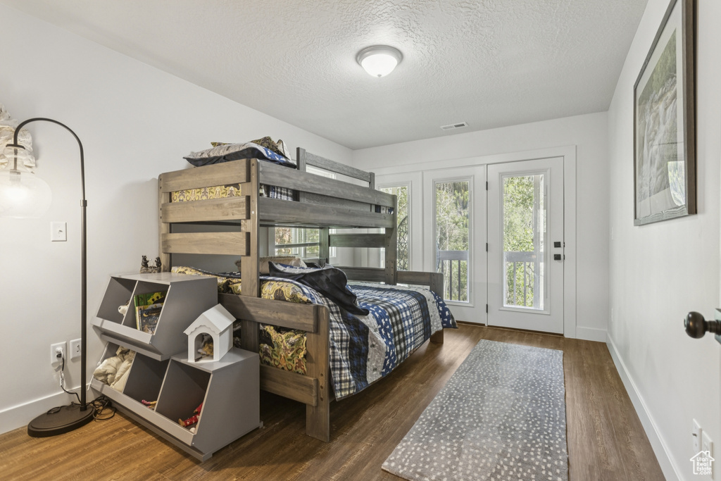 Bedroom with access to exterior, a textured ceiling, and wood finished floors