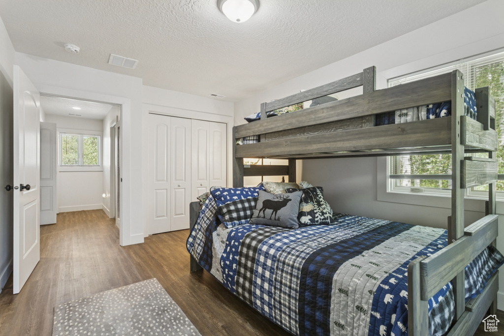 Bedroom with wood finished floors, a textured ceiling, and a closet